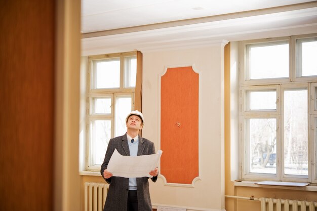 Ingénieur ou architecte dans le casque blanc avec le plan. Intérieur de reconstruction.