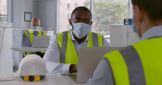 Ingénieur et architecte en masque de sécurité discutent au bureau