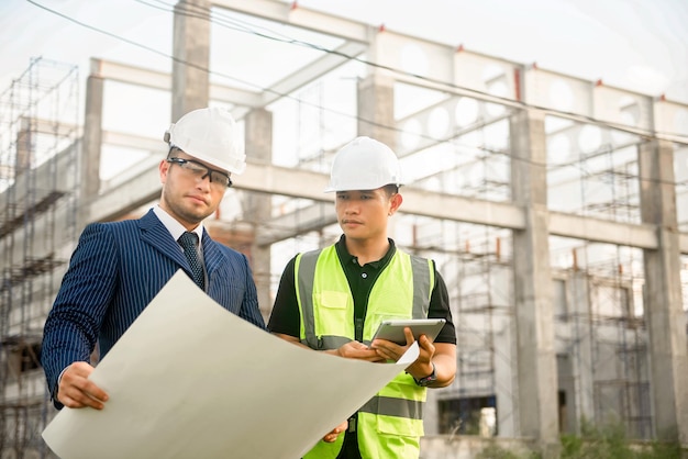 L'ingénieur et l'architecte surveillent l'avancement du plan de construction du bâtiment et vérifient son exactitude.