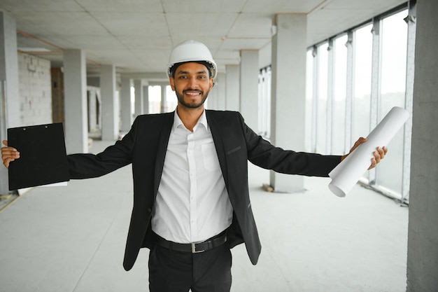 Ingénieur asiatique bel homme ou architecte avec casque de sécurité blanc sur le chantier de construction debout dans la construction de bâtiments modernes