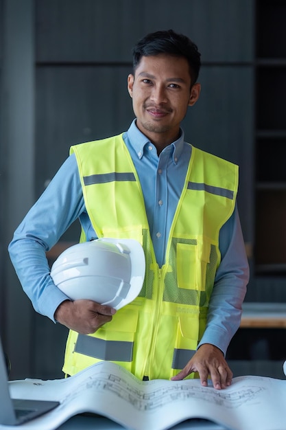 Ingénieur asiatique bel homme ou architecte impatient avec un casque de sécurité blanc sur un chantier de construction