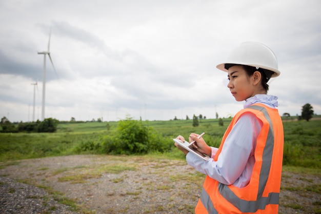 Ingénieur asiatique avec casque à l'aide d'un ordinateur tablette pc inspectant et travaillant à la ferme éolienne Power Generator Station