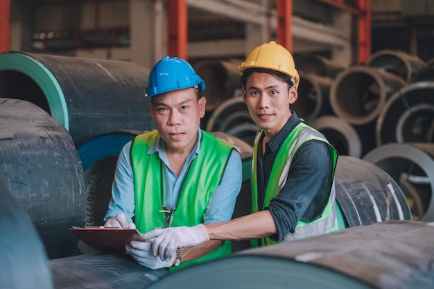 Ingénieur asiatique directeur d'usine et employé mécanicien dans un casque de sécurité parlant et inspectant à l'intérieur de l'usine