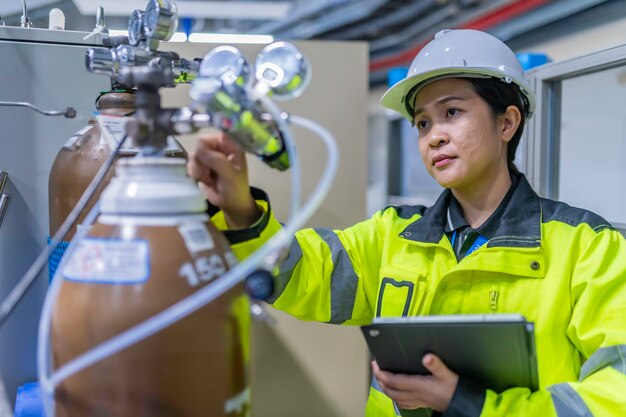 Ingénieur asiatique travaillant dans la salle d'opérationLes Thaïlandais portent un casqueIl a travaillé avec diligence et patience, elle a vérifié le régulateur de valve du réservoir d'hydrogène