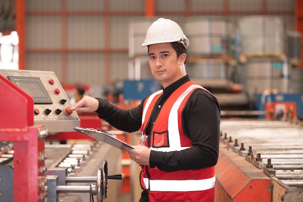 Ingénieur asiatique travaillant dur dans l'usine de machines de contrôle de sécurité du casque de sécurité des employés d'usine