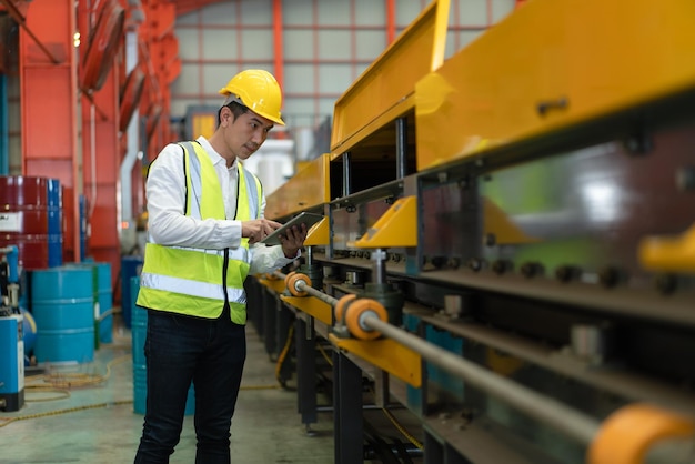 Ingénieur asiatique utilisant une machine de contrôle de tablette dans une usine de fabrication industrielle