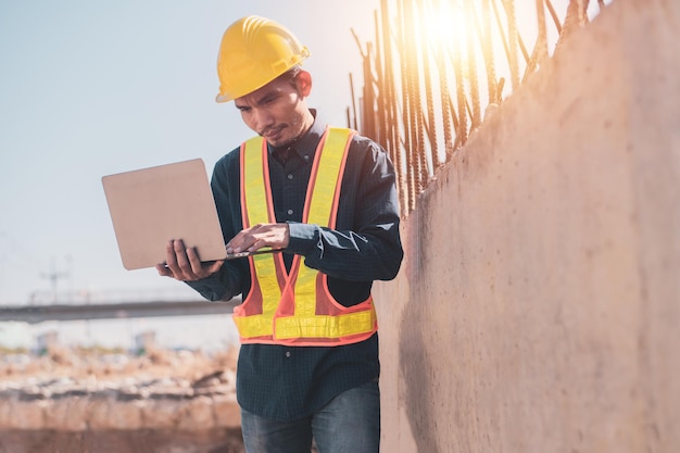 Ingénieur asiatique utilisant un ordinateur portable sur la construction du site, ordinateur de l'arpenteur sur le chantier