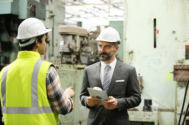 Ingénieur assidu tenant une tablette numérique dans les mains tout en travaillant dans la vue de profil de l'usine de fabrication