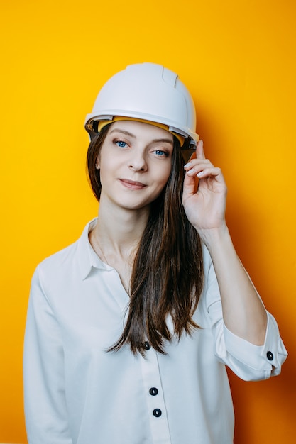 Ingénieur en casque blanc. Affiche de sécurité. Femme en chemise blanche touche le casque.