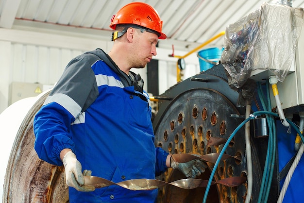 L'ingénieur en casque inspecte et répare l'équipement à gaz de la chaufferie Nettoyage et entretien de la chaudière à gaz