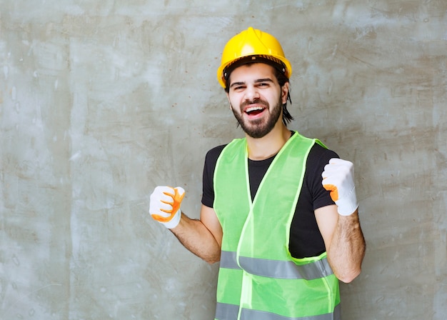 Ingénieur en casque jaune et gants industriels montrant un signe de satisfaction