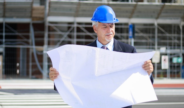 Ingénieur en chef lisant un plan avant d'un chantier de construction