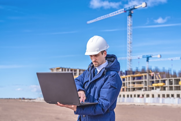 Ingénieur civil dans un casque blanc et une veste bleue sur le site