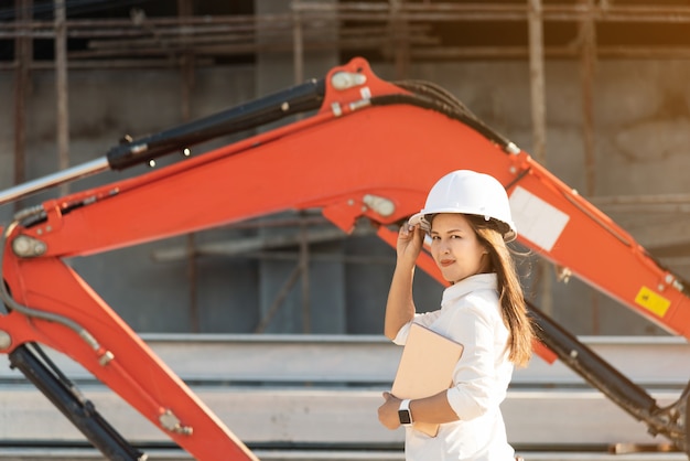 Ingénieur civil de femme asiatique avec un chantier de construction de casque de sécurité blanc.