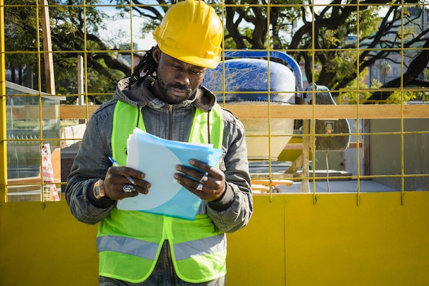 ingénieur civil homme noir avec casque sur le chantier de construction debout en train de lire un espace de copie de dossier