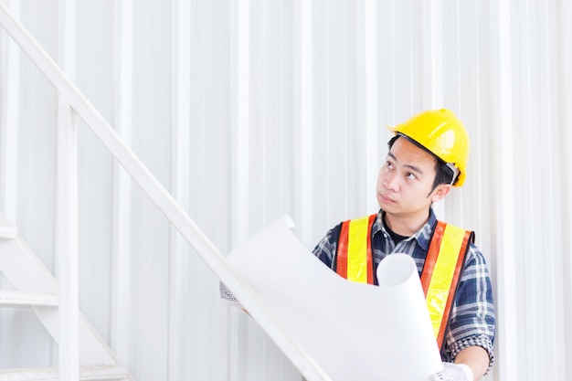 Ingénieur civil intelligent porter un casque de sécurité et tenir construction