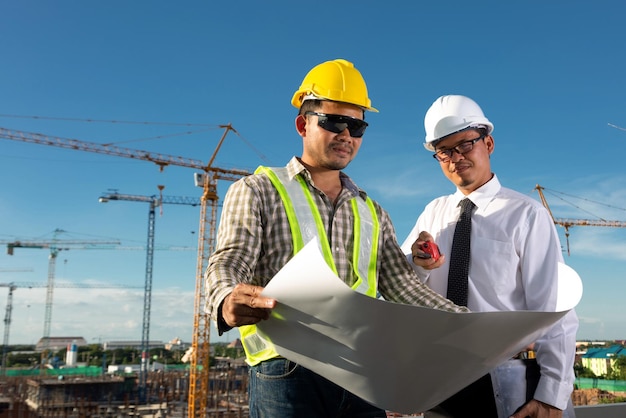 Ingénieur civil vérifiant le travail avec walkietalkie pour la communication avec l'équipe de gestion sur le chantier de construction