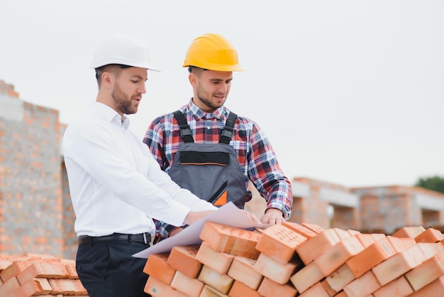 Ingénieur et constructeur en casques discutant du plan sur le chantier de construction