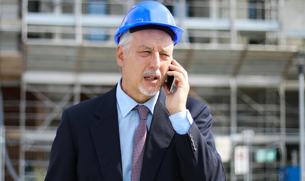 Ingénieur constructeur sur un chantier de construction parlant au téléphone