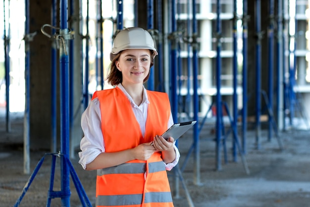 Ingénieur de construction féminin. Architecte avec une tablette sur un chantier de construction. Jeune femme à la recherche, lieu de chantier sur fond. Notion de construction.