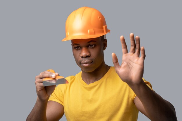 Un ingénieur en construction à la peau foncée dans un bonnet de protection tenant un flotteur