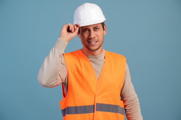 Photo ingénieur en construction souriant posant avec un léger sourire dans un casque à sa tête isolé sur fond bleu clair. banque d'images