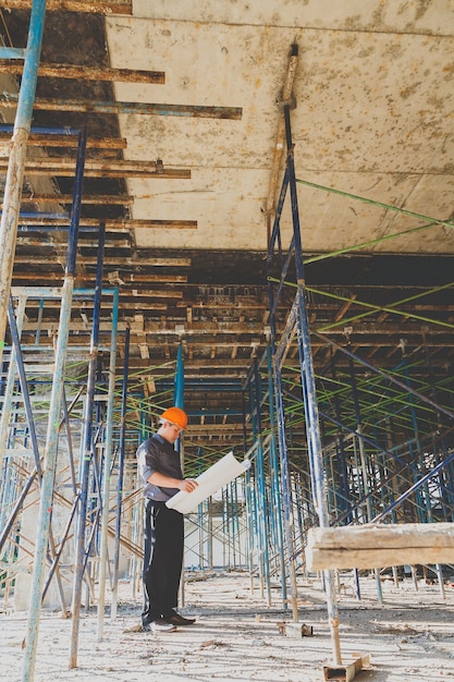 Ingénieur ou contremaître avec blueprint dans le chantier de construction