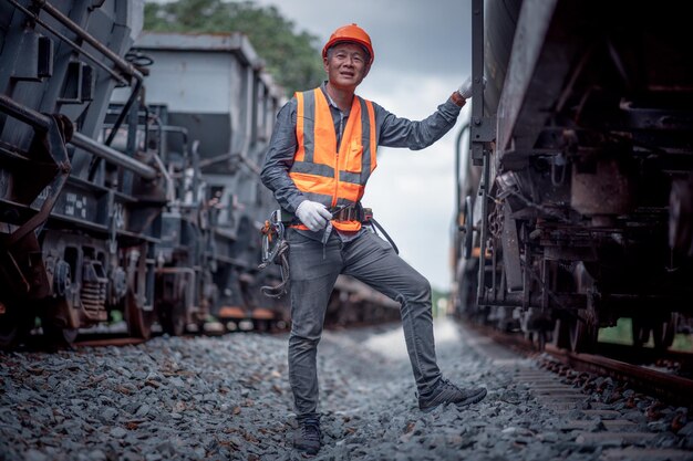 Photo ingénieur en cours d'inspection et de vérification du processus de construction du chemin de fer et vérification des travaux à la gare ferroviaire ingénieur portant un uniforme de sécurité et un casque de sécurité au travail