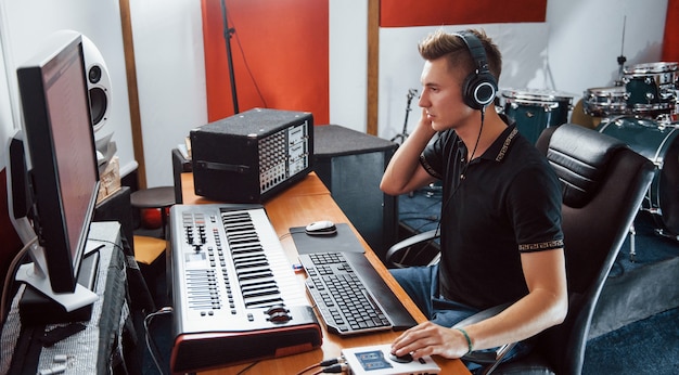 Ingénieur du son au casque travaillant et mixant de la musique à l'intérieur du studio.