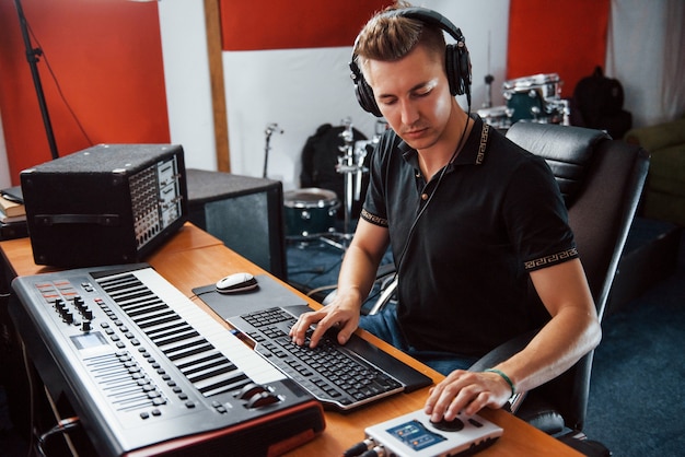 Ingénieur du son au casque travaillant et mixant de la musique à l'intérieur du studio.