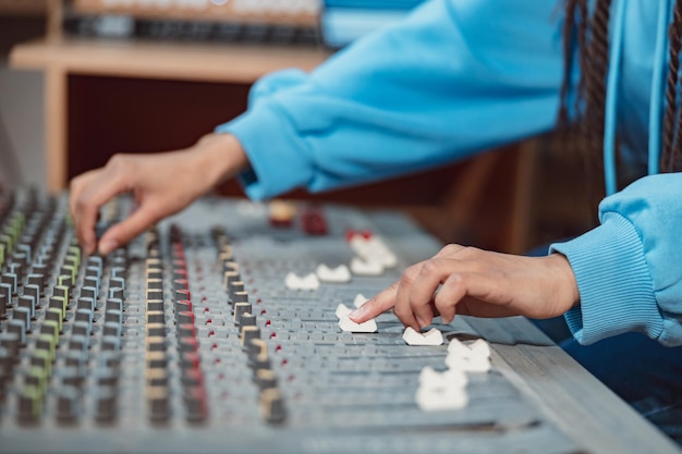 Photo ingénieur du son musicien producteur mains à l'aide d'une table de mixage et d'un logiciel pour créer une chanson en studio d'enregistrement