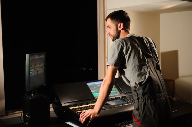 Un ingénieur d'éclairage travaille avec les techniciens d'éclairage sur le contrôle du spectacle de concert. Mélangeur d'éclairage professionnel, console de mixage. Equipement pour concerts