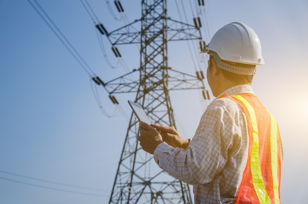 Ingénieur électricien tenant et utilisant une tablette numérique avec fond de tour haute tension