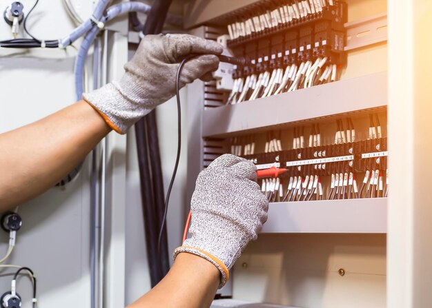 Un ingénieur électricien teste le fonctionnement de l'armoire de commande électrique pour l'entretien