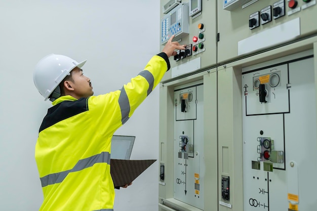 Ingénieur électricien vérifiant la tension à l'armoire de distribution électrique dans la salle de contrôlemaintenance préventive