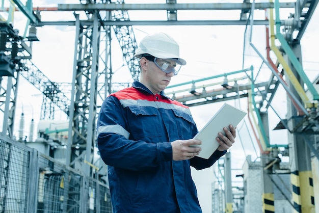 Un ingénieur en énergie inspecte l'équipement moderne d'une sous-station électrique avant la mise en service Énergie et industrie Réparation programmée d'équipements électriques