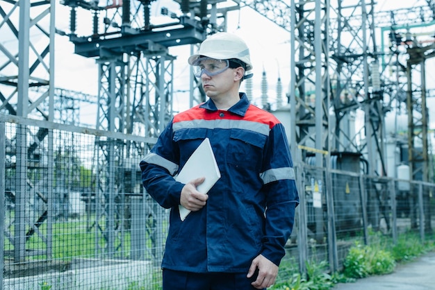 Un ingénieur en énergie inspecte l'équipement moderne d'une sous-station électrique avant la mise en service Énergie et industrie Réparation programmée d'équipements électriques