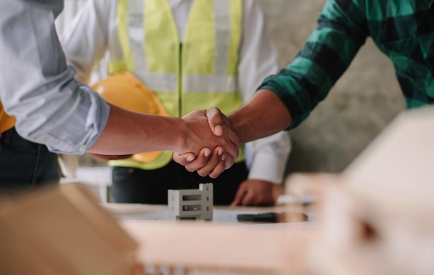 L'ingénieur et l'entrepreneur se donnent la main après la signature du contratIls ont un projet de construction moderne ensemble un concept de coopération réussixA