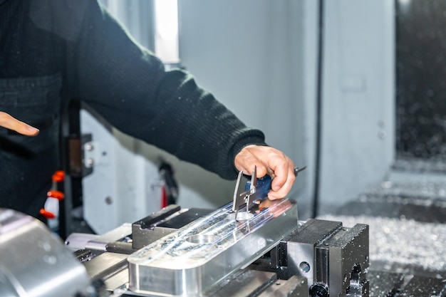 L'ingénieur expert utilisant l'étrier dans l'atelier pour mesurer la dimension des pièces d'assemblage dans une usine moderne CNC