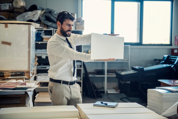 Un ingénieur graphique regardant une épreuve imprimée à l'imprimerie