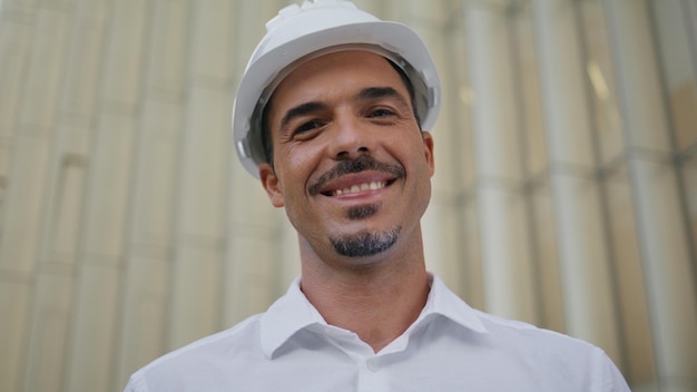 Ingénieur heureux posant un portrait d'architecture moderne homme latin enlevant son chapeau