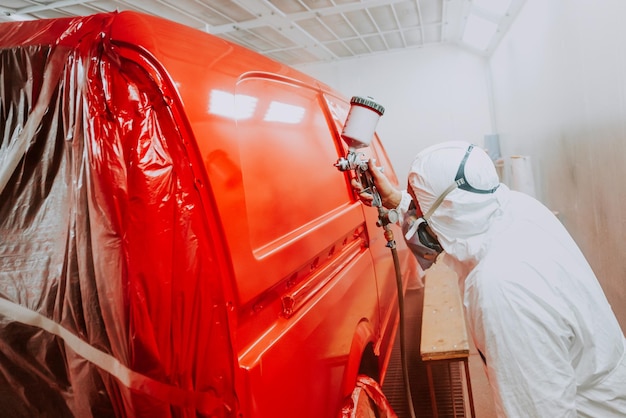 Ingénieur de l'industrie automobile peignant et travaillant sur une carrosserie rouge d'une voiture et portant un équipement de protectionxA