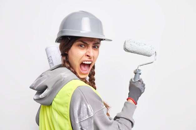 Un ingénieur industriel émotionnel met en œuvre un projet de construction dans des peintures vivantes avec des cris de rouleaux et demande avec colère de ne pas la déranger pendant qu'il travaille porte un casque de protection et un uniforme. Meilleur réparateur de tous les temps