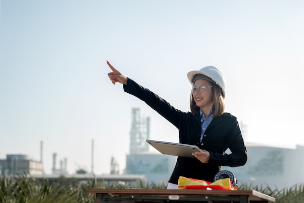 Photo ingénieur industriel féminin dans un casque travaillant sur le site de la raffinerie de pétrole et de la centrale électrique, l'industrie, l'ingénieur et le concept de sécurité.