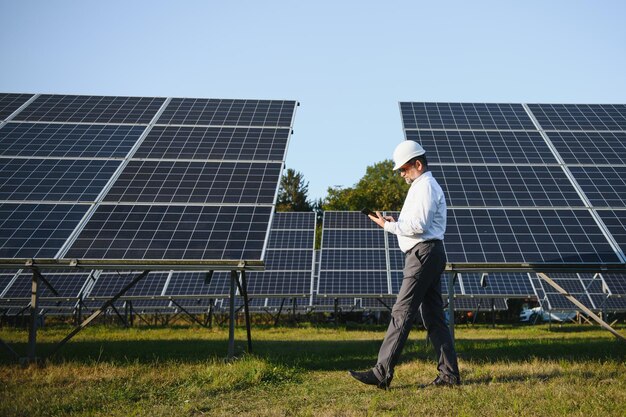 Un ingénieur industriel senior se promène dans le champ des panneaux solaires pour l'examen.