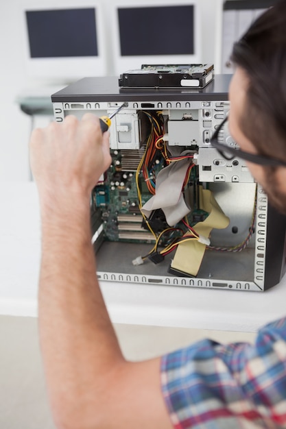 Ingénieur en informatique travaillant sur une console cassée avec un tournevis