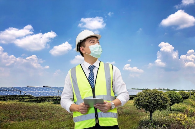 Ingénieur d'inspection tenant une tablette contre une ferme solaire pour l'alimentation électrique sur le site.