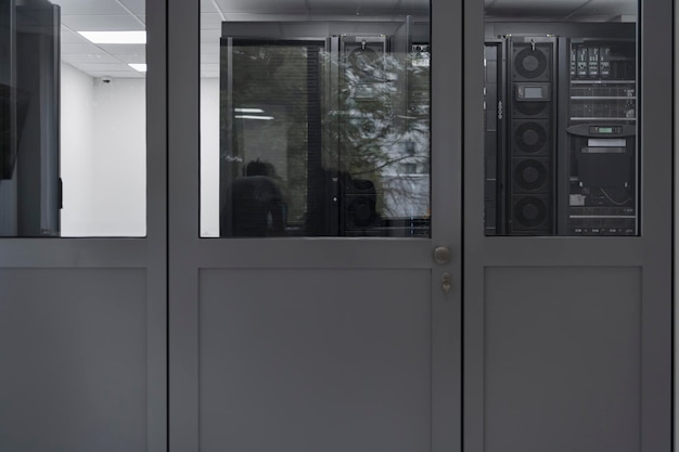 Ingénieur logiciel travaillant sur un ordinateur portable dans une salle de serveurs moderne. Monitoring Room Big Data Scientist dans le reflet de la porte d'entrée. Photo de haute qualité