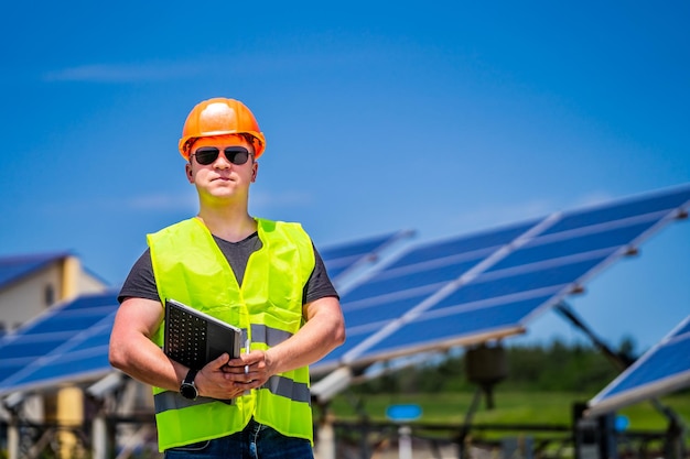Ingénieur en lunettes de soleil et casque sur fond de centrale à énergie solaire