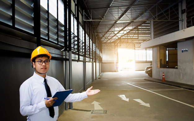 Ingénieur mâle vérifiant en usine avec note sur le bloc-notes ou l&#39;industrie flou fond